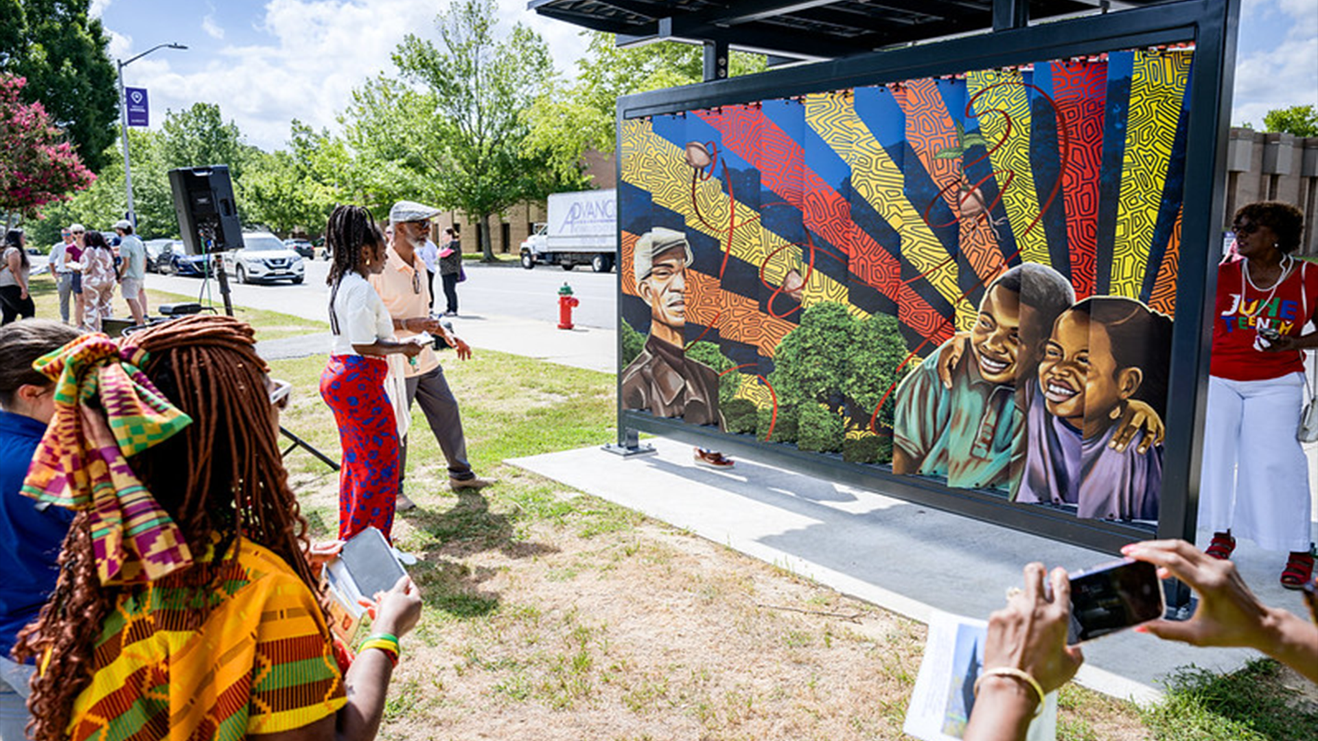 Artist explaining the art on the side of the shelter facing Town Common